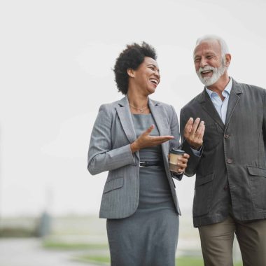 Shot of two successful multi-ethnic business people talking and having fun while walking during a coffee break outdoors.